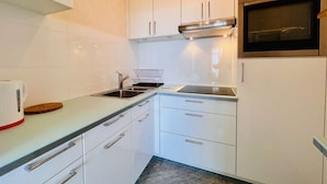 A modern kitchen with white cabinets, stainless steel appliances, and a built-in oven. - QUIBERON - Studio - 38m² - Sea view (QUIBERON)