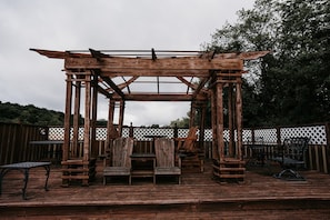 Guests can sit and relax in the gazebo, surrounded by a wooden deck and white lattice fence.