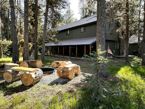 Eine rustikale Lodge mit überdachter Veranda, Holzsitzgelegenheiten und einem Kamin aus Stein.