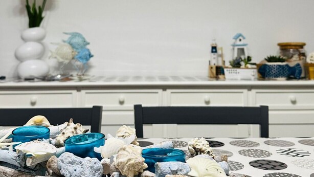 Una mesa de comedor con conchas marinas y un jarrón de flores.
