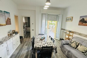 A dining area with a patterned tablecloth, a sofa, and a kitchen in the background.