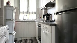 Una cocina compacta con lavadora, un lavabo y un refrigerador de acero inoxidable.