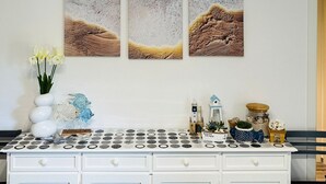 Un aparador blanco con varios cajones, un florero con flores y objetos decorativos encima.