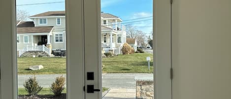 A double door leading to a driveway with a lawn and a house in the background.