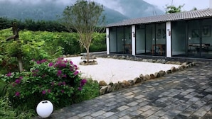A traditional building with a tiled roof, surrounded by a garden with flowering plants and a stone pathway. - Zuisusheng Guesthouse (Xi'an)