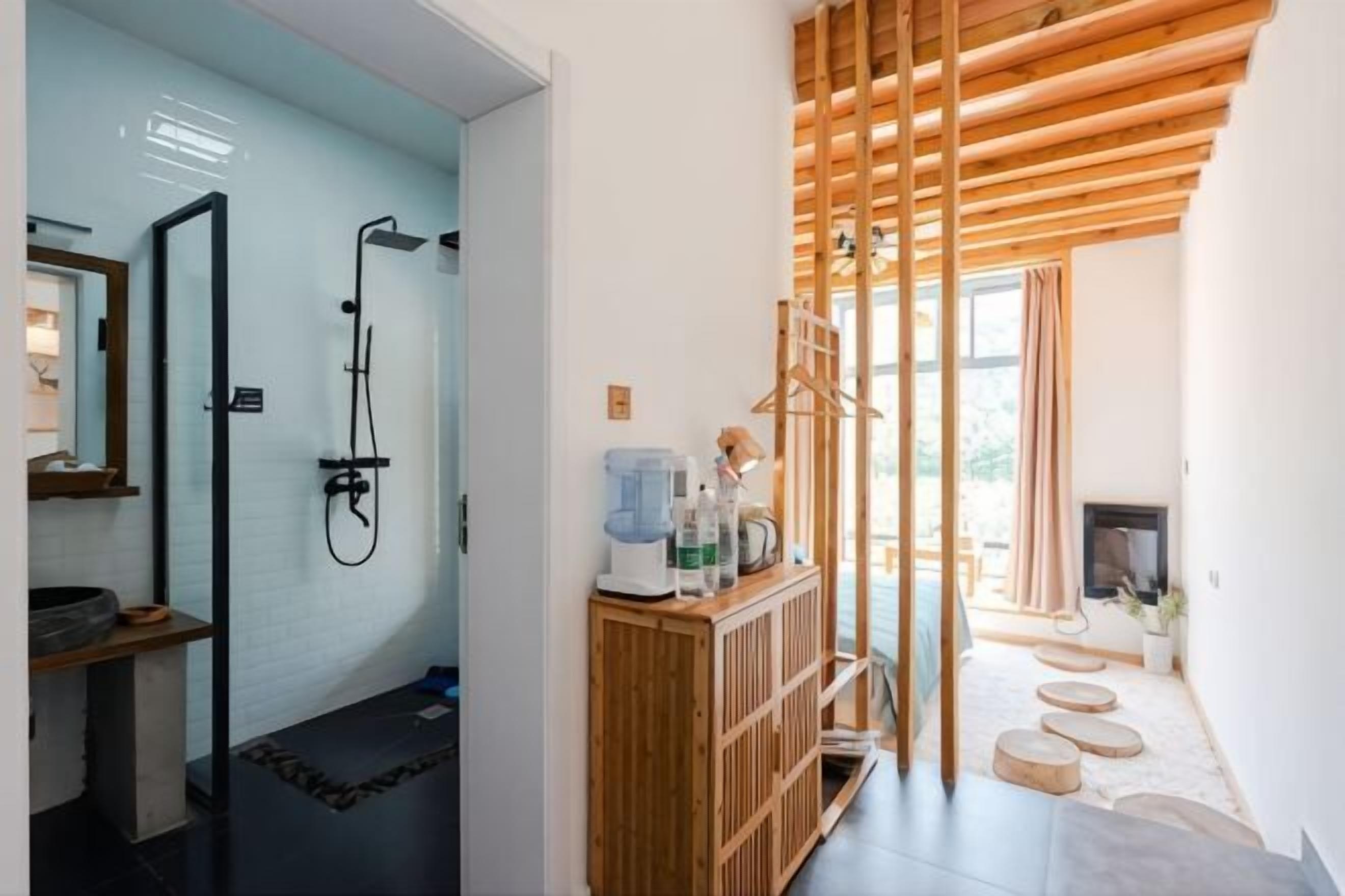 Een badkamer met een douche, wastafel en spiegel. Er is een houten kastje met toiletartikelen en een televisietoestel.