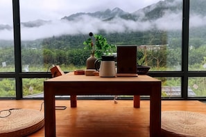 Una mesa de madera con una computadora portátil, una cafetera y un florero con una planta.
