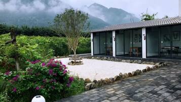 A traditional building with a tiled roof, a stone pathway, and a garden with flowering plants.