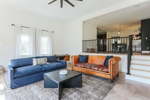 Ein Wohnzimmer mit einem blauen Sofa, einem braunen Sofa, einem Couchtisch und einer Treppe, die in einen oberen Bereich führt.