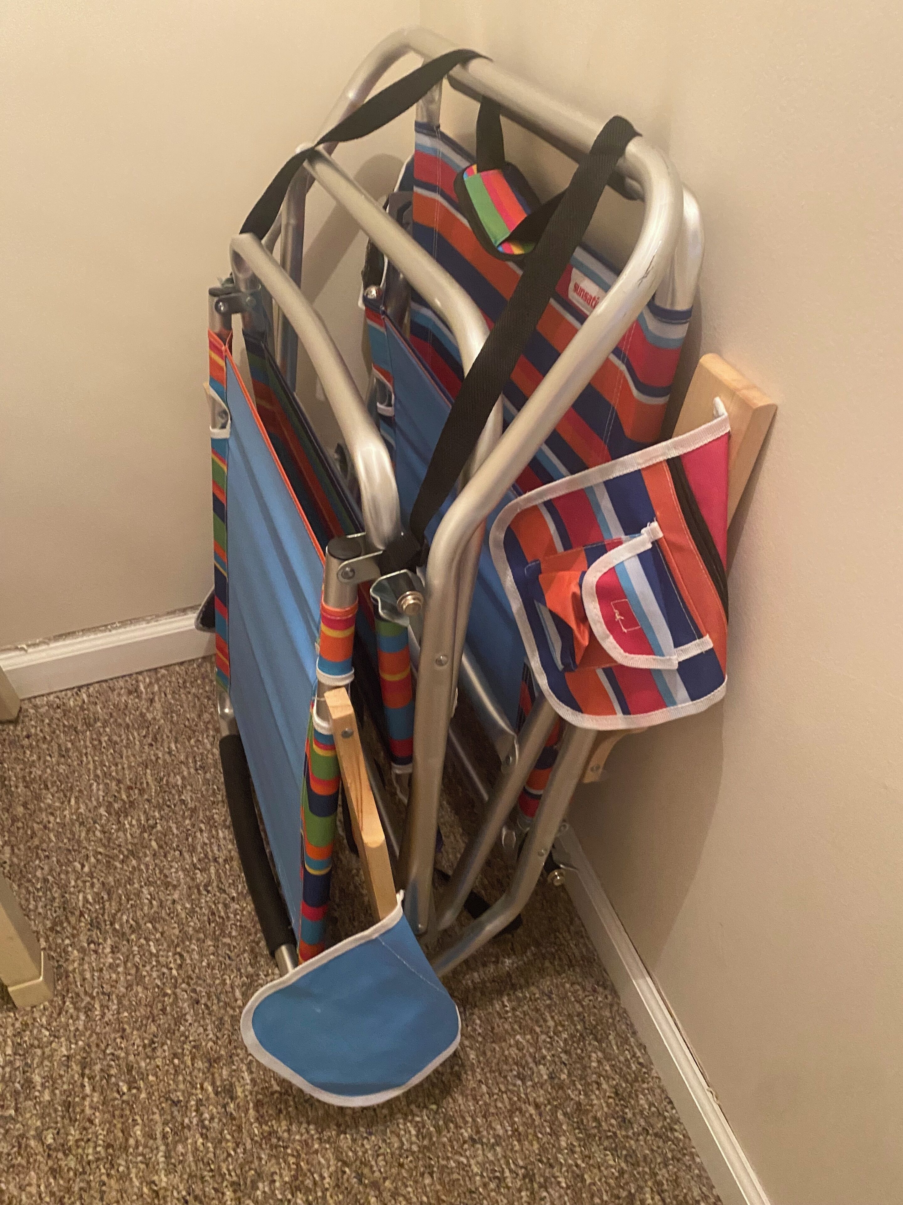 A corner of a room with a metal cart holding several colorful bags and a blue shoe.