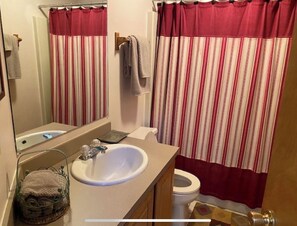 Une salle de bain avec un lavabo blanc, un miroir, un porte-serviettes et un rideau de douche à rayures.