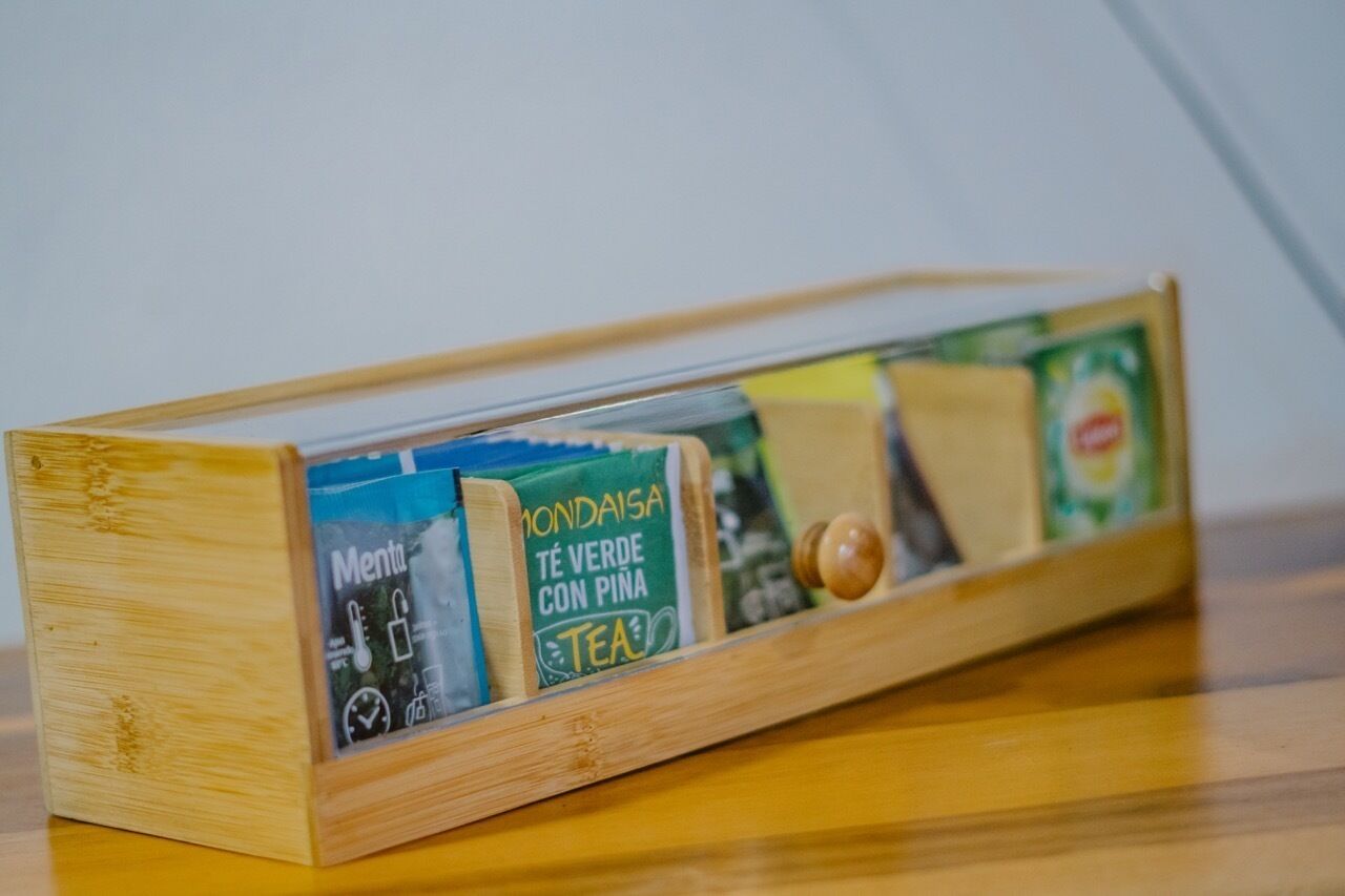 Una caja de madera con bolsitas de té y un termómetro.