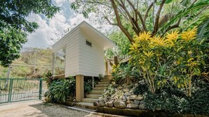 Una casa de dos pisos con fachada blanca, un pequeño balcón y una escalera de piedra que conduce a la entrada.
