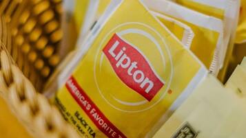 Una cesta que contiene bolsitas de té Lipton y una caja blanca etiquetada con 'Sin calorías'.