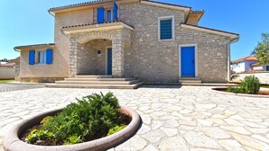 A stone house with a tiled roof, a front porch, and a small garden bed in the foreground. - House 2326/110968 (Istria - Vodnjan), 5000m from the beach (Vodnjan)