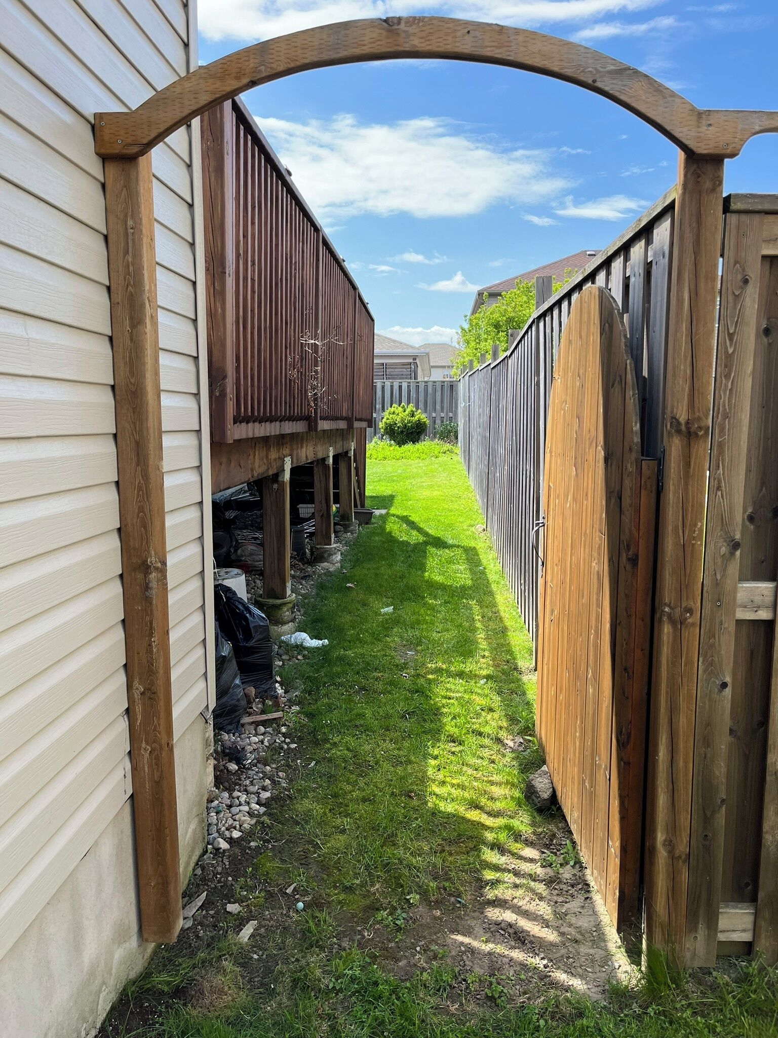 A narrow pathway between two wooden fences with a clear sky above.