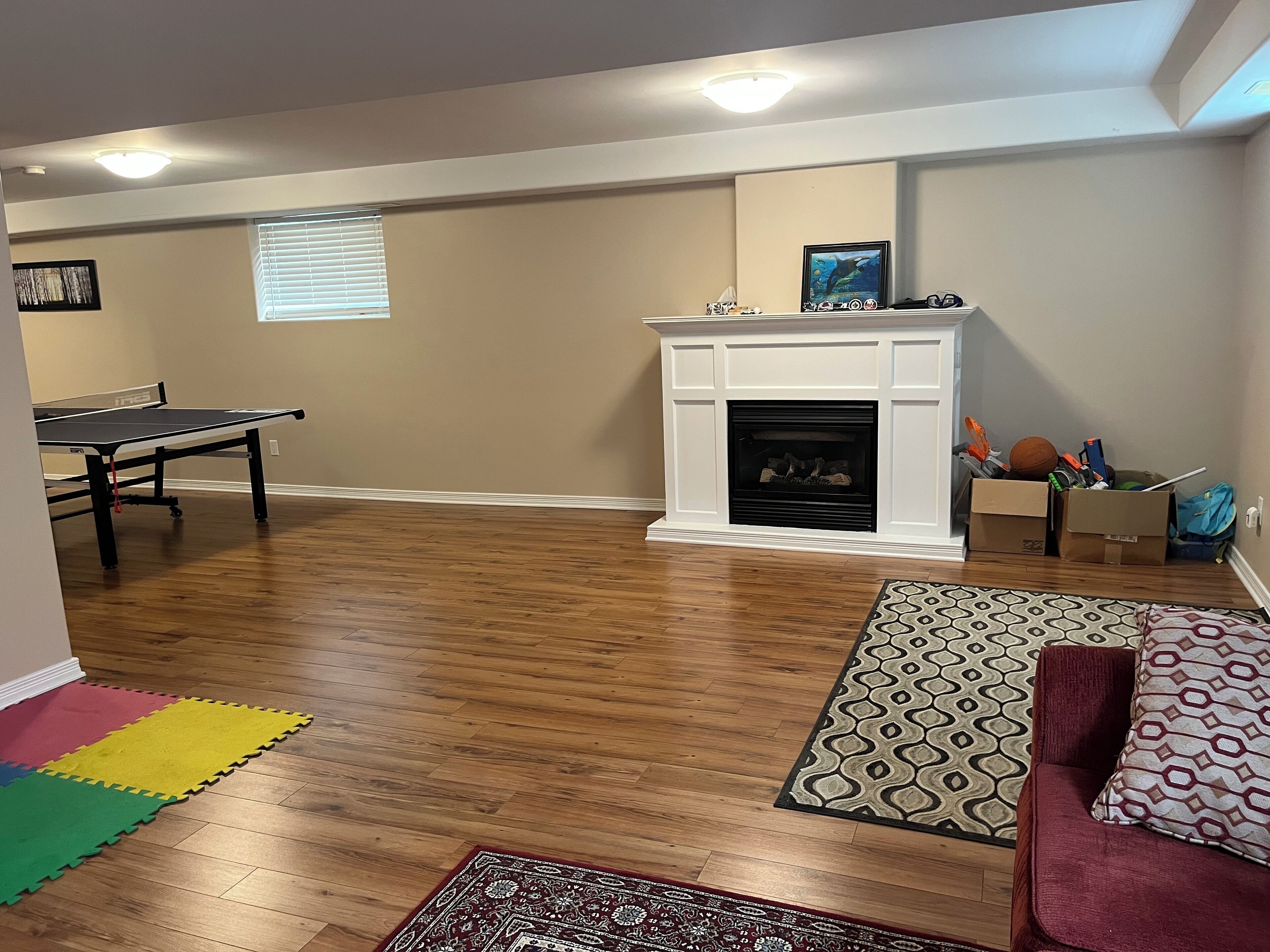 A living room with a ping pong table, a fireplace, and a patterned rug.