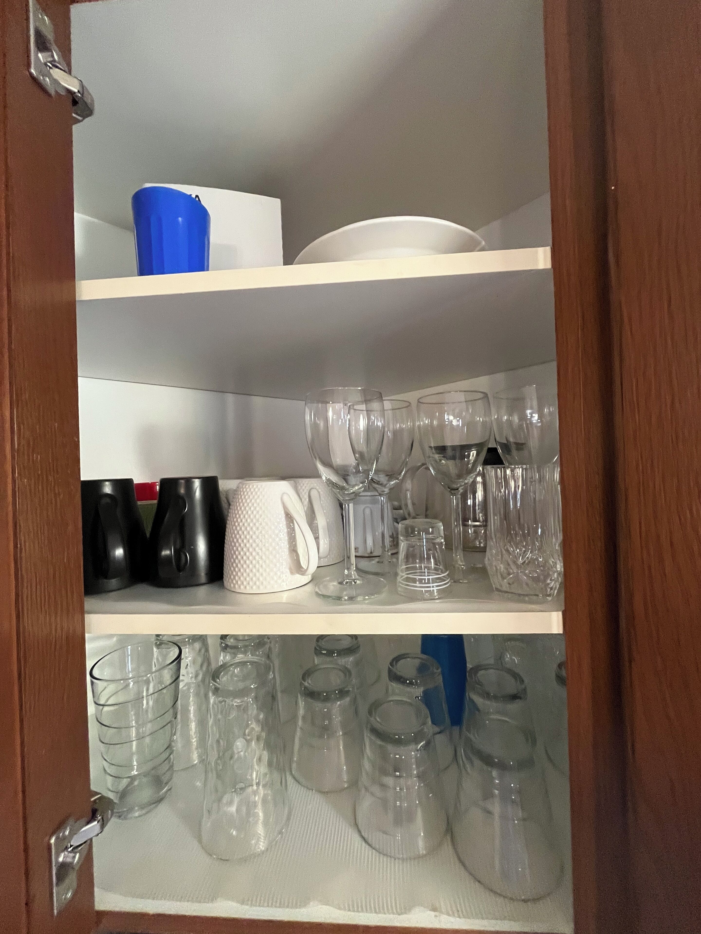 A cabinet with shelves containing various glassware and mugs.