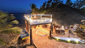 A beachfront property with a dining area, outdoor seating, and a boat dock. - Casa Cenote Hotel (Tulum)