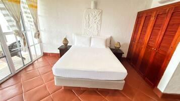 Quarto com uma cama grande, uma porta de correr de vidro, um guarda-roupa de madeira e uma peça decorativa na parede.