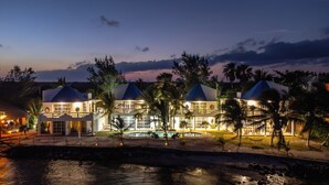 A large, multi-story hotel with a pool area, surrounded by palm trees and a body of water. - Casa Cenote Hotel (Tulum)