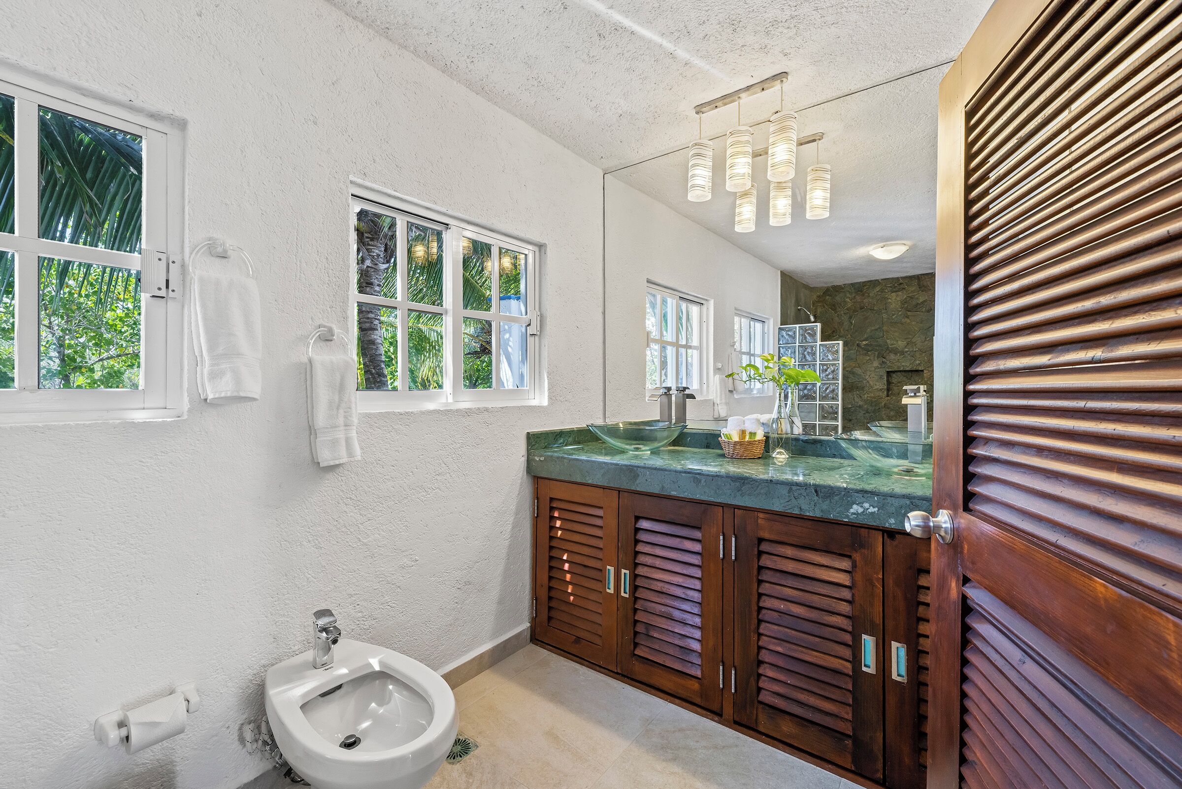 Une salle de bain équipée d’un bidet, d’un lavabo, d’un miroir et de meubles en bois.
