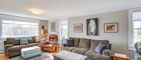 A spacious living room with a large window, a fireplace, and a comfortable seating area.