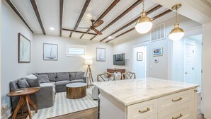 A spacious living room with a sofa, coffee table, and a dining area with a marble countertop. - The Bogard Only 4 Blocks to King! Unit A (Charleston)
