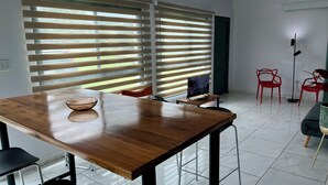 A modern dining area with a wooden table, chairs, and a large window with blinds.