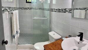 Ein modernes Badezimmer mit einer Duschkabine, einer weißen Toilette und einem hölzernen Waschtisch.