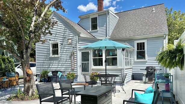 A patio area with outdoor furniture, a table, and a blue umbrella.