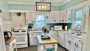 A modern kitchen with white cabinetry, a wooden countertop, and a central island.
