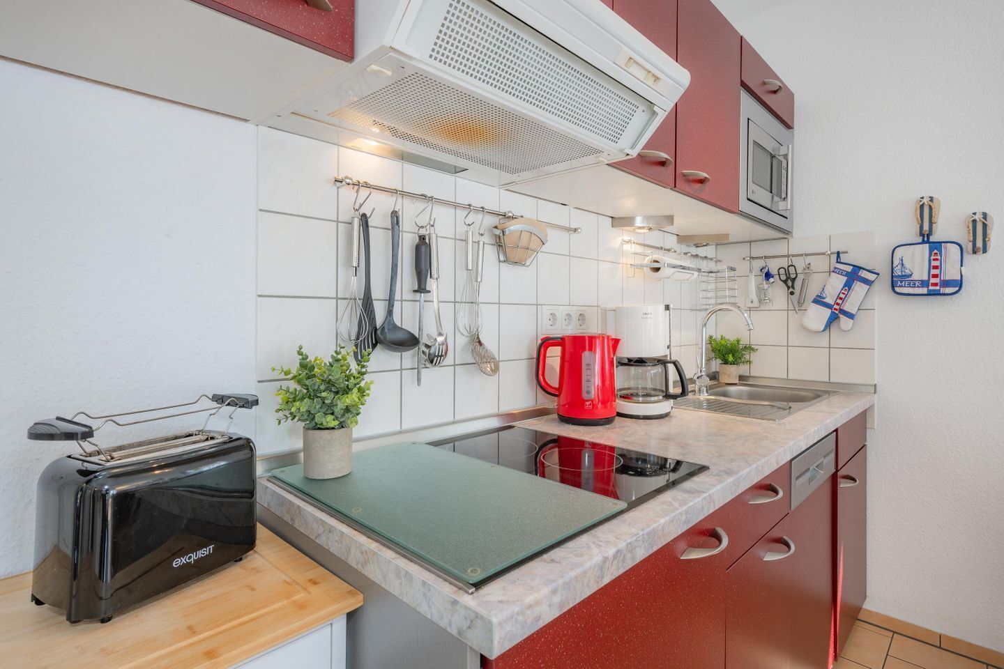 Una cocina moderna con tostadora, hervidor y cafetera sobre la encimera.
