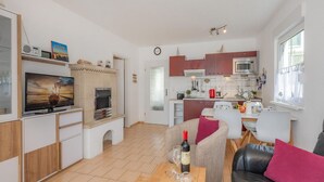 Un salon moderne doté d’un téléviseur à écran plat, d’une cheminée et d’un coin repas avec une table mise pour deux personnes.
