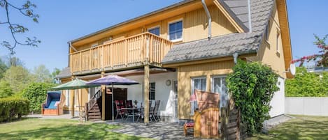 A two-story house with a balcony, a covered patio, and a play area with a slide.