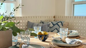 A dining area with a wooden table set for two, featuring woven placemats, plates, cutlery, and glasses. - Oceanfront 5BR Hot Tub & Swim Spa (Galveston)
