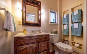A bathroom with a wooden vanity, a toilet, and a towel rack with multiple towels. - Loren's Lookout- pet friendly, on the way to Yellowstone National Park (Cody)