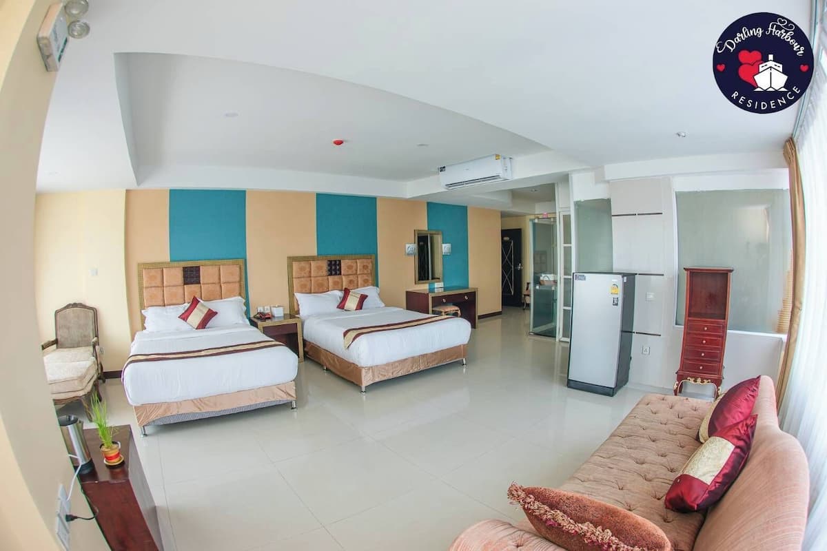 Une chambre d’hôtel avec deux lits, un canapé, un réfrigérateur et un mini-bar.