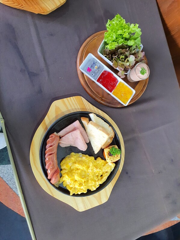 A breakfast tray with eggs, ham, toast, and a small salad on a wooden board. - Darling Harbour Residence - Pattaya (Pattaya)