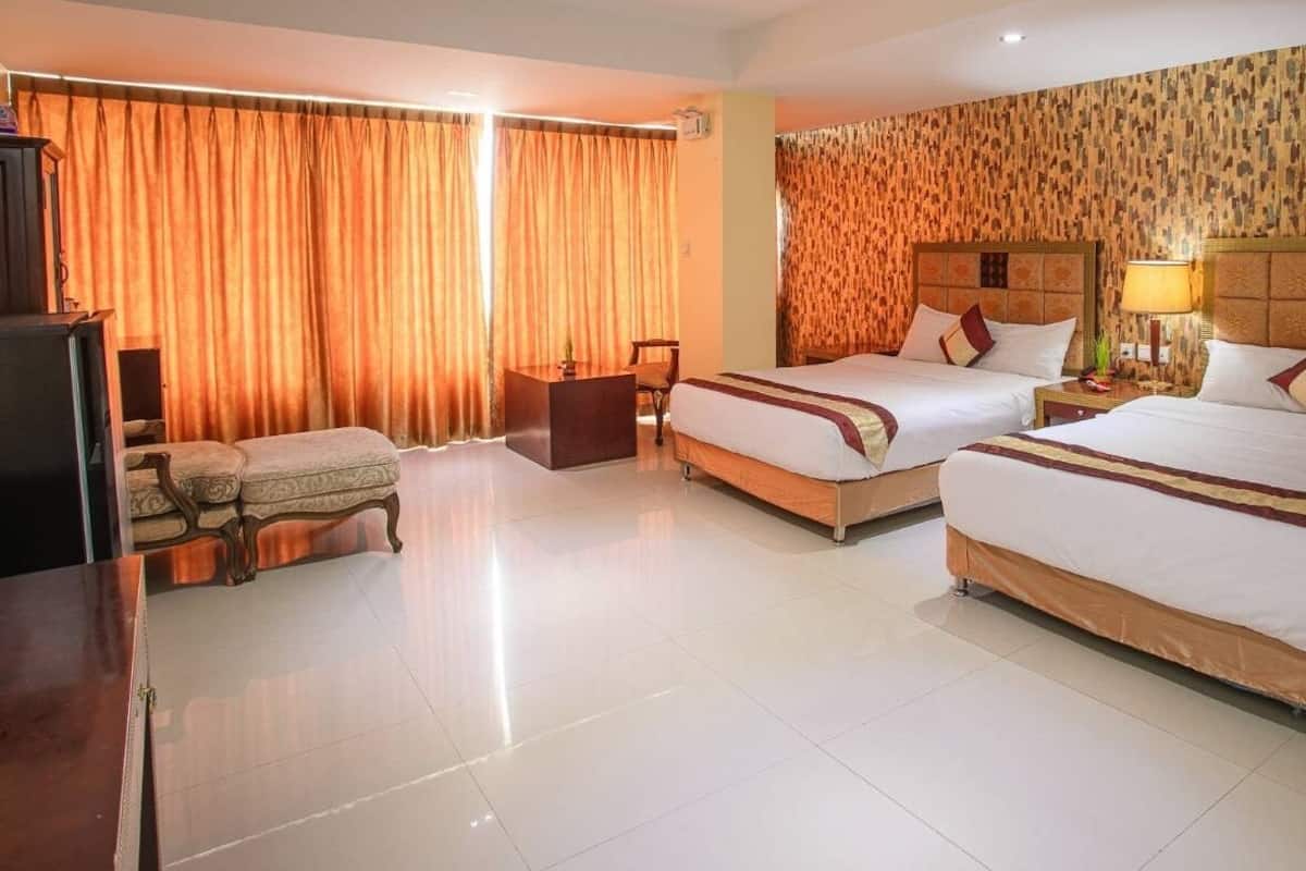 Une chambre d’hôtel avec deux lits, un bureau, une chaise et une télévision.