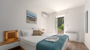 A modern bedroom with a large bed, a view of greenery through an open door, and a radiator on the wall. - House Ada (Istria - Poreč) (Poreč)
