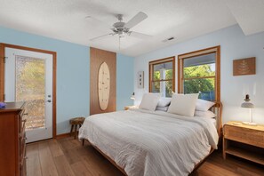 A bedroom with a bed, wooden floor, ceiling fan, and a door with a view of the outside. - Cloudbreak: Pet Friendly, Oceanside, Hot Tub, Community Amenities! (Duck)