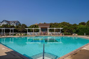A swimming pool with a no diving sign, lounge chairs, and a covered area with a sign reading "Fours Seasons."