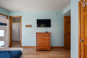 A room with a wooden dresser, a television mounted on the wall, and a door.