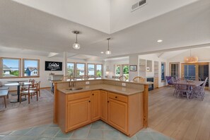 Una cocina amplia con una isla grande, armarios de madera y un comedor con mesa y sillas.