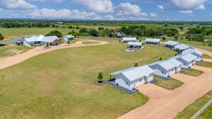 A large, open facility with multiple buildings, including a central structure with a covered outdoor area and several smaller buildings with flat roofs. - Cross Mountain Cottages 3 | Cozy Porch & Pavilion (Fredericksburg)
