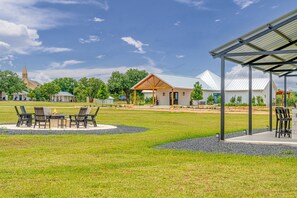 Ett rymligt utomhusområde med en eldstad, sittplatser och en överbyggd paviljong.