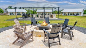 An outdoor patio with Adirondack chairs, a fire pit, and a covered seating area. - Cross Mountain Cottages 7 | Ensuite Baths & Porch (Fredericksburg)