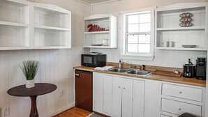 A kitchen with white cabinetry, a microwave, a coffee maker, and a sink.
