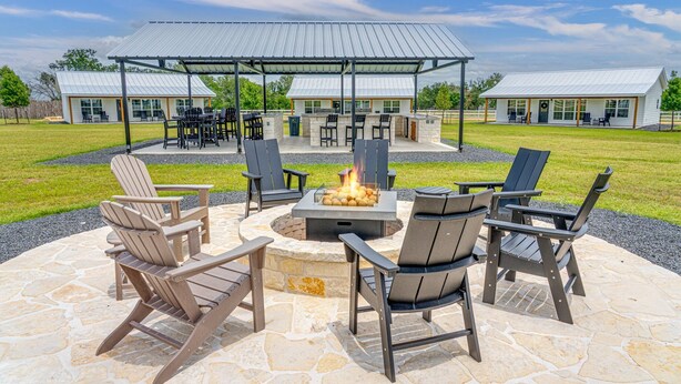 Une terrasse extérieure avec des fauteuils Adirondack, un foyer et un espace salon abrité.
